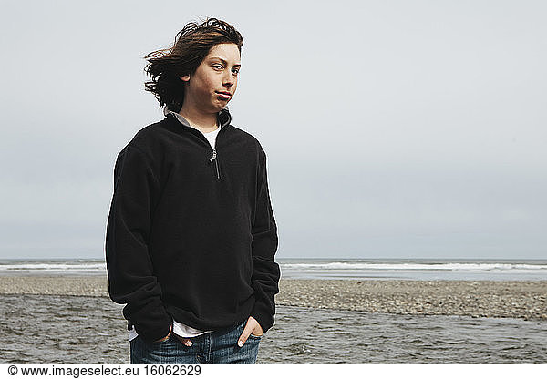 Portrait of moody teenage boy on beach