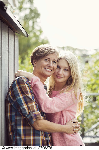 Portrait of mother and daughter embracing at yard