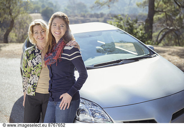 Portrait of mother and daughter outside car