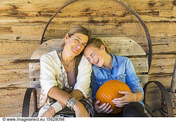 portrait of mother and her teen age daughter holding pumpkin