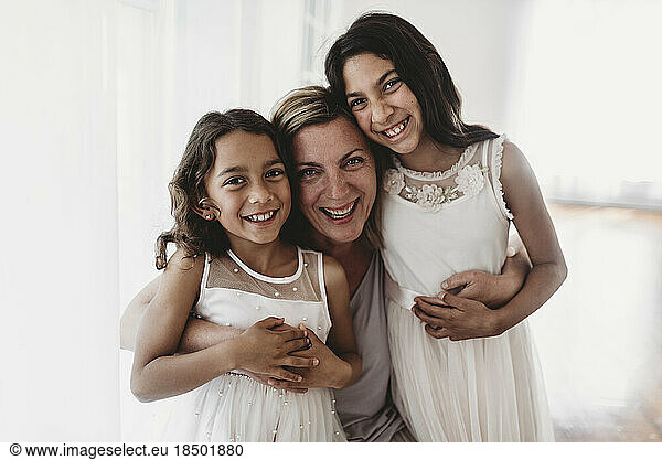 Portrait of mother and two daughters in natural light studio smiling
