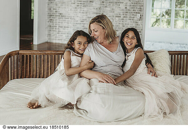 Portrait of mother and two daughters on couch in natural light studio