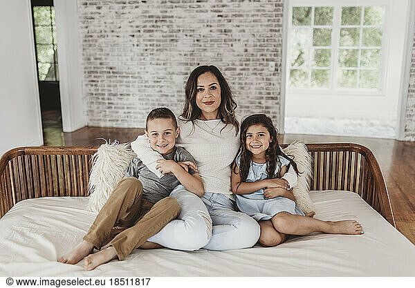 Portrait of mother  daughter  and son sitting on couch and smiling