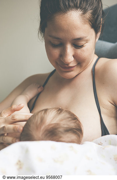 Portrait of mother smiling and breast-feeding little baby