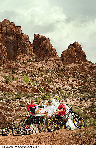 Portrait of mountain bikers standing on rocks against mountains
