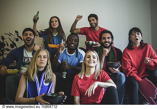 Portrait of multi-ethnic friends watching soccer match while sitting at home
