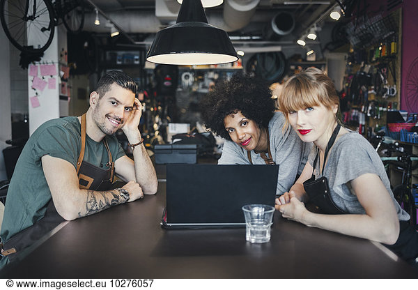 Portrait of multi-ethnic mechanics with laptop at table