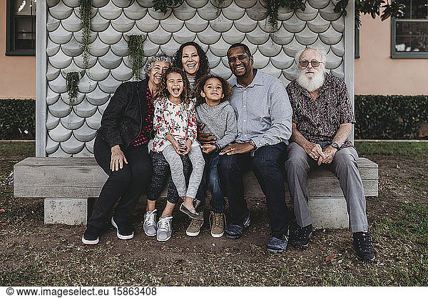 Portrait of multigenerational family sitting on park bench outside