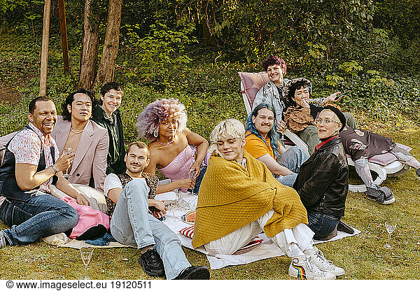 Portrait of multiracial friends from LGBTQ community sitting together in back yard