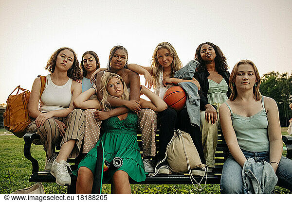 Portrait of multiracial teenage girls sitting together on bench