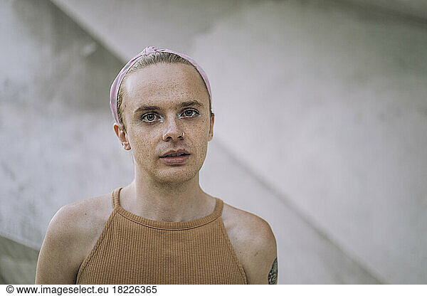 Portrait of non-binary person against wall