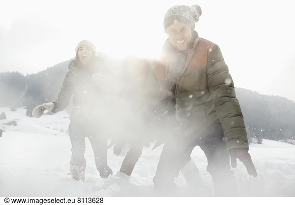 Portrait of playful friends enjoying snowball fight in field