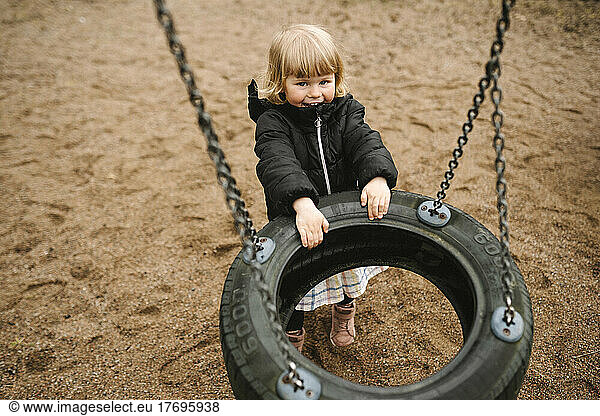 Portrait of playful girl pulling tire swing in park