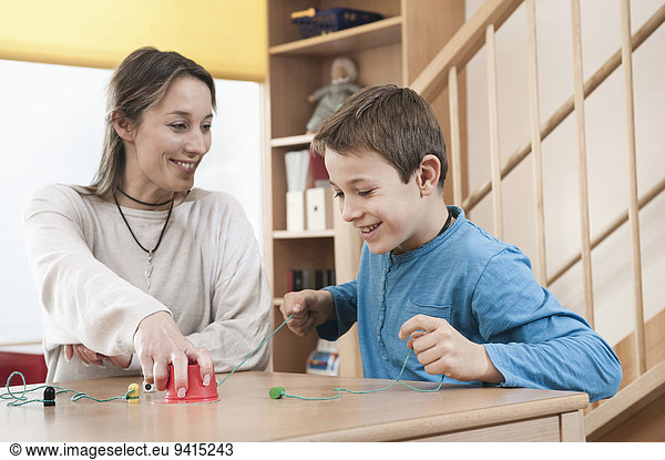 Portrait of playing boy and female childcare assistant