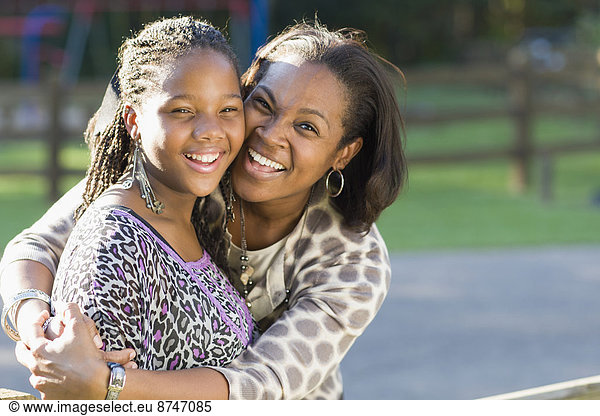 Portrait of pre-teen girl and mother  hugging outdoors