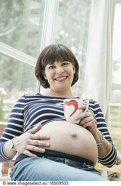 Portrait of pregnant woman with coffee mug