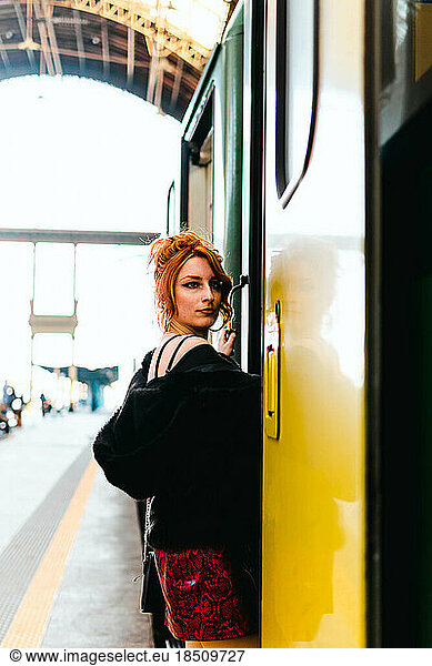 portrait of red-haired woman getting on the train in train station
