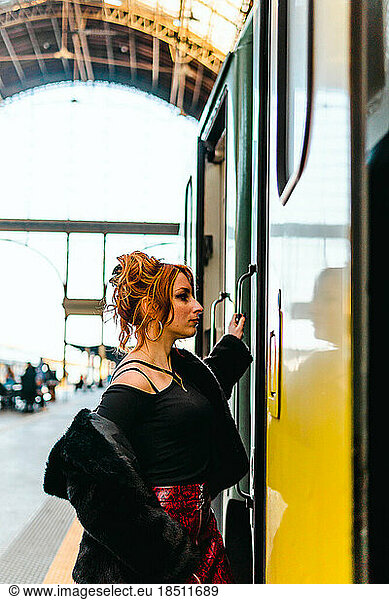 portrait of red-haired woman getting on the train is train station