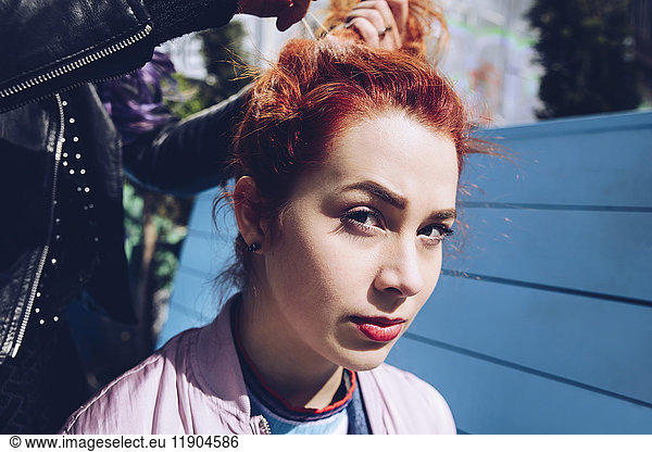 Portrait of redhead woman with friend tying hair