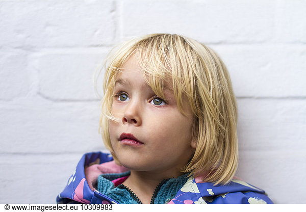 Portrait of sad little girl in front of whie wall
