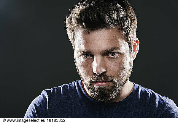 Portrait of sad man with beard in front of black background