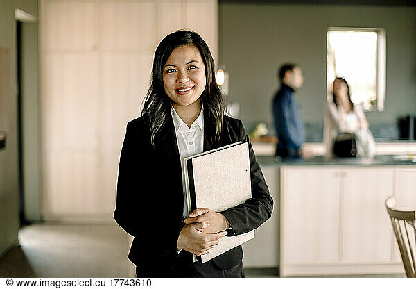 Portrait of saleswoman with folder standing at new home