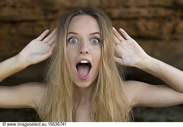 Portrait of screaming young woman raising hands
