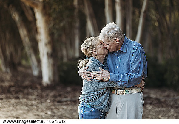 Portrait of senior adult retired couple kissing in forest