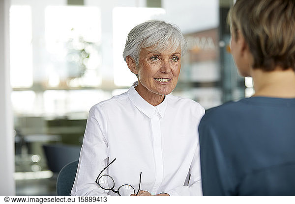 Portrait of senior businesswoman talking to colleague in office