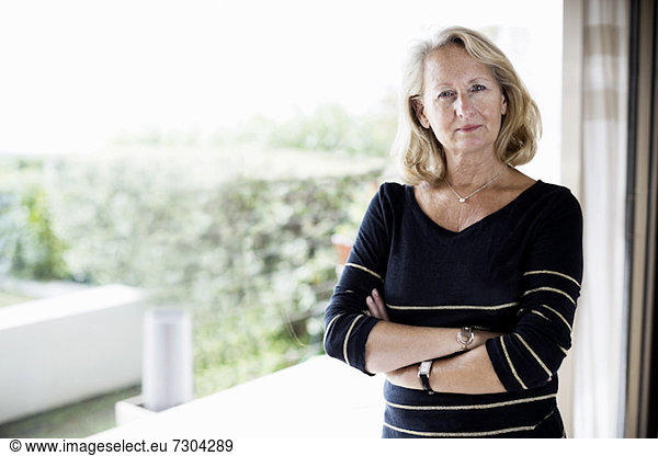 Portrait of senior businesswoman with arms crossed standing at office