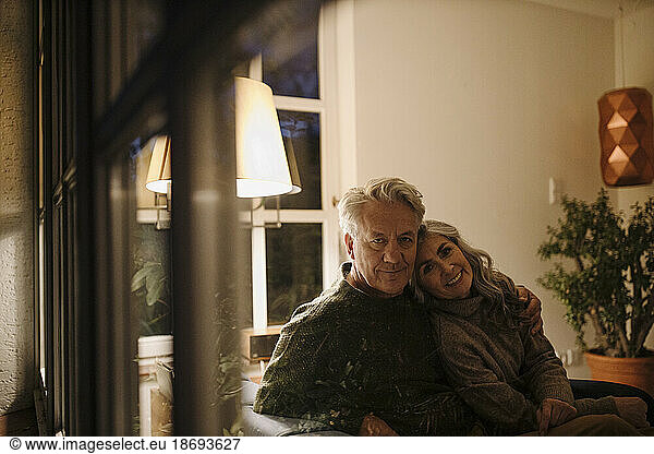 Portrait of senior couple relaxing on couch at home at night
