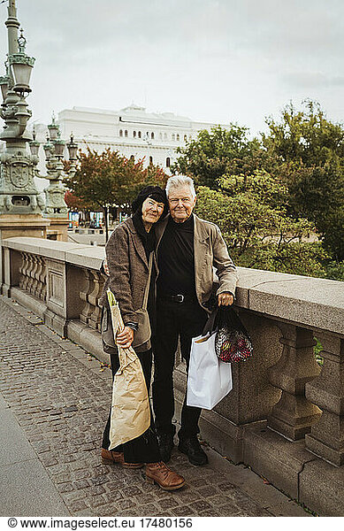 Portrait of senior couple standing on bridge in city