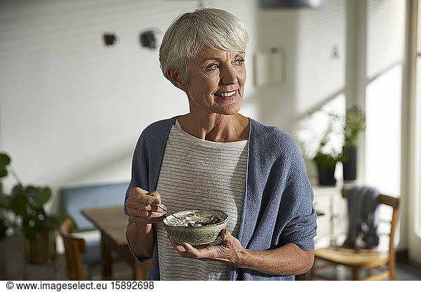 Portrait of senior woman holding bowl of granola with yoghurt and berries