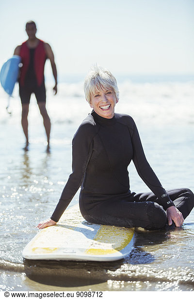 Portrait of senior woman on surfboard at beach