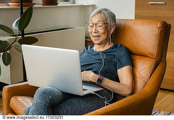 Portrait of senior woman smiling while using laptop at home