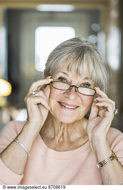 Portrait of senior woman smiling while wearing glasses indoors