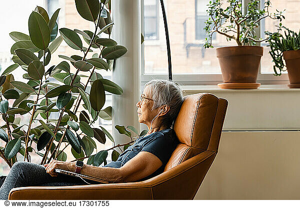 Portrait of senior woman wearing earphones and relaxing at home