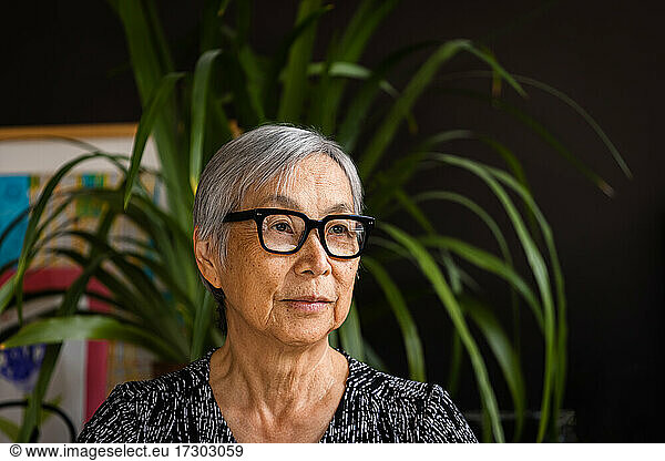 Portrait of Senior Woman wearing glasses at home with plants