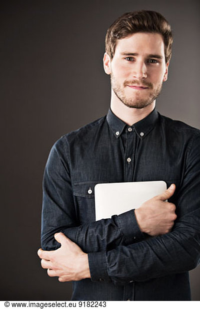 Portrait of serious businessman holding digital tablet