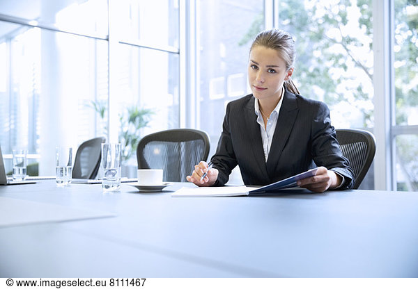 Portrait of serious businesswoman reviewing paperwork in conference room