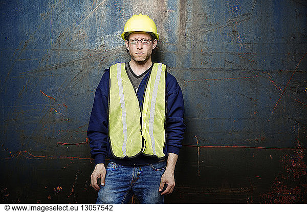 Portrait of serious male worker standing against metal wall