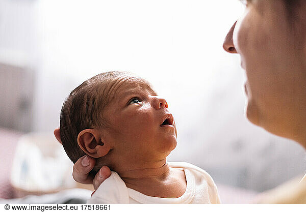 Portrait of serious newborn baby looking at his mother.