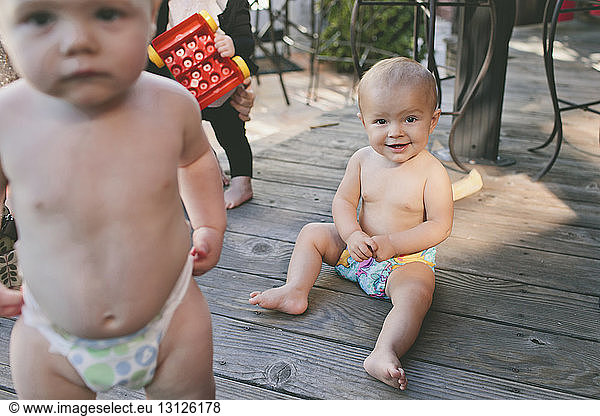 Portrait of shirtless baby girls on floorboard at birthday party