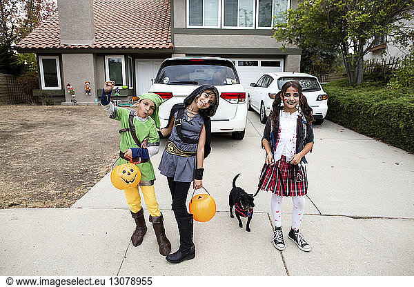 Portrait of siblings in Halloween costumes while standing in yard