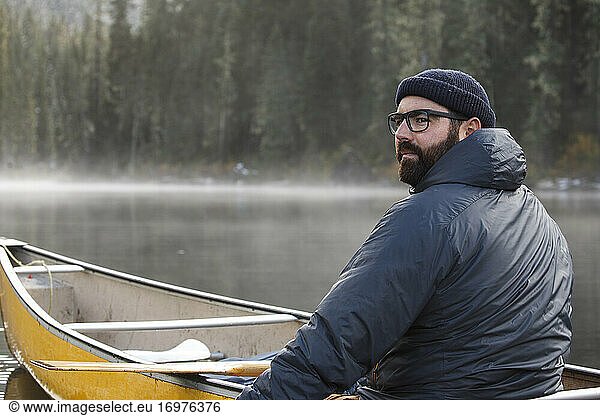 Portrait of sincere man canoeing on lake on a foggy  misty day