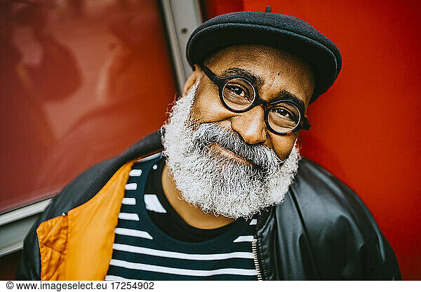 Portrait of smiling bearded senior male hipster wearing eyeglasses and beret