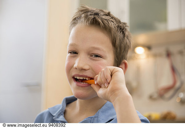 Portrait of smiling boy eating carrot