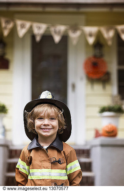 Portrait of smiling boy in Halloween costume standing against house