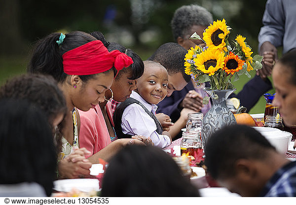 Portrait of smiling boy sitting with family and friends at table while having food