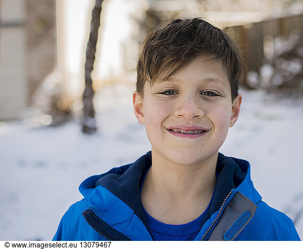 Portrait of smiling boy with braces wearing warm clothing during winter